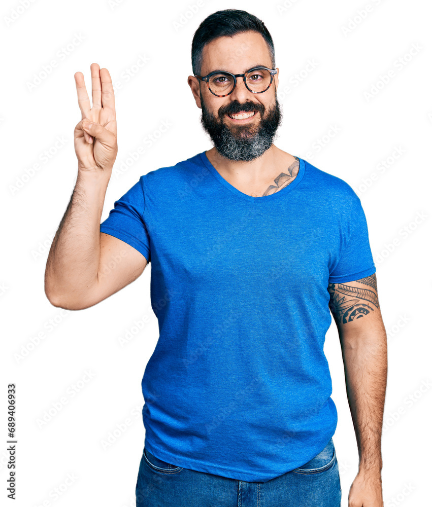 Naklejka premium Hispanic man with beard wearing casual t shirt and glasses showing and pointing up with fingers number three while smiling confident and happy.