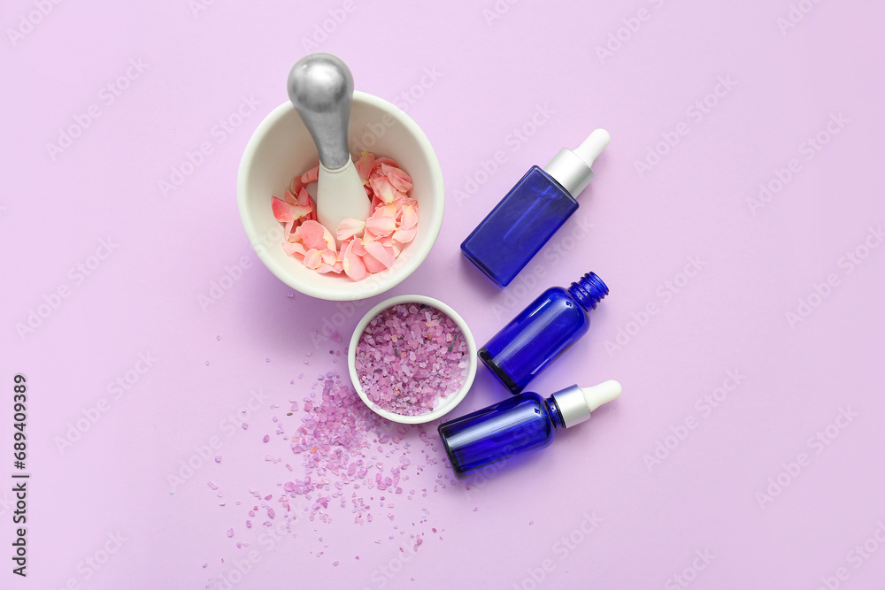 Bottles of cosmetic oil with rose extract, mortar and petals on purple background Bottles of cosmetic oil with rose extract, mortar and petals on purple background