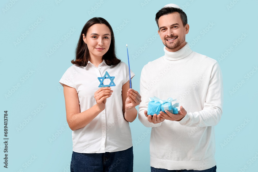 Lovely couple with David star, gift boxes and candle on blue background. Hanukkah celebration Lovely couple with David star, gift boxes and candle on blue background. Hanukkah celebration