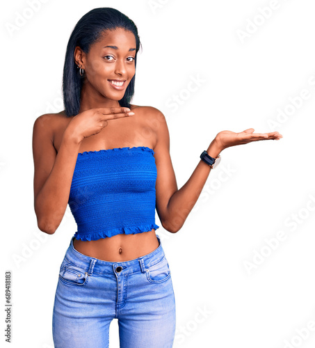 Young african american woman wearing casual summer clothes amazed and smiling to the camera while presenting with hand and pointing with finger. photo