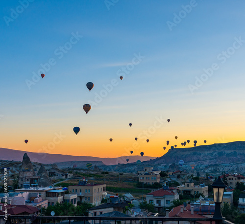 View of Hot Air Balloons at Sunrise from Hotel Terrace in Goreme in Cappadocia, Turkey.