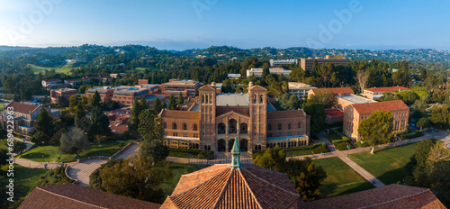 Aerial view of UCLA campus featuring classical architecture, red-brick buildings, green spaces, and a distinctive domed structure under a clear blue sky.
