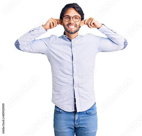 Handsome hispanic man wearing business shirt and glasses smiling pulling ears with fingers, funny gesture. audition problem