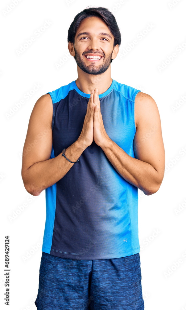 Handsome hispanic man wearing sportswear praying with hands together asking for forgiveness smiling confident. Handsome hispanic man wearing sportswear praying with hands together asking for forgiveness smiling confident.