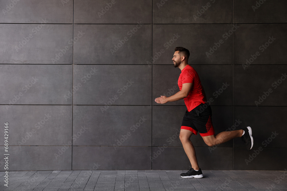 Young man running near building outdoors. Space for text Young man running near building outdoors. Space for text