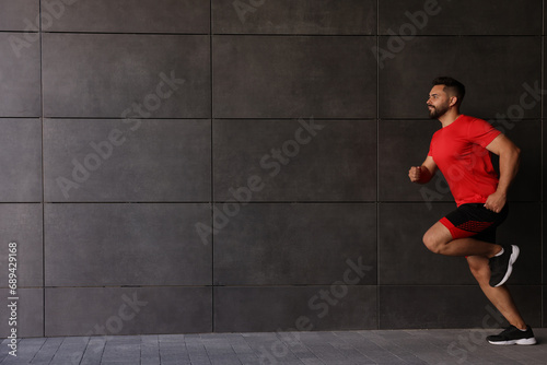 Young man running near building outdoors. Space for text © New Africa