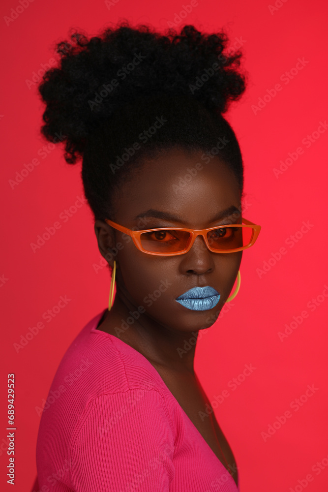 Fashionable portrait of beautiful woman with stylish sunglasses on coral background Fashionable portrait of beautiful woman with stylish sunglasses on coral background