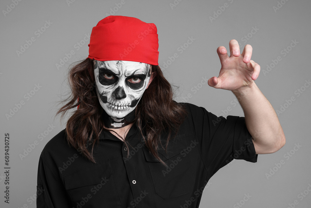 Man in scary pirate costume with skull makeup on light grey background. Halloween celebration