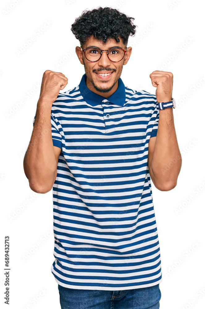 Young arab man wearing casual clothes and glasses celebrating surprised and amazed for success with arms raised and open eyes. winner concept. Young arab man wearing casual clothes and glasses celebrating surprised and amazed for success with arms raised and open eyes. winner concept.
