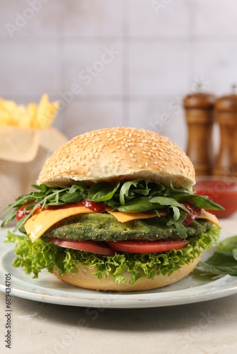 Tasty vegetarian burger with spinach cutlet  cheese and vegetables served on white table  closeup
