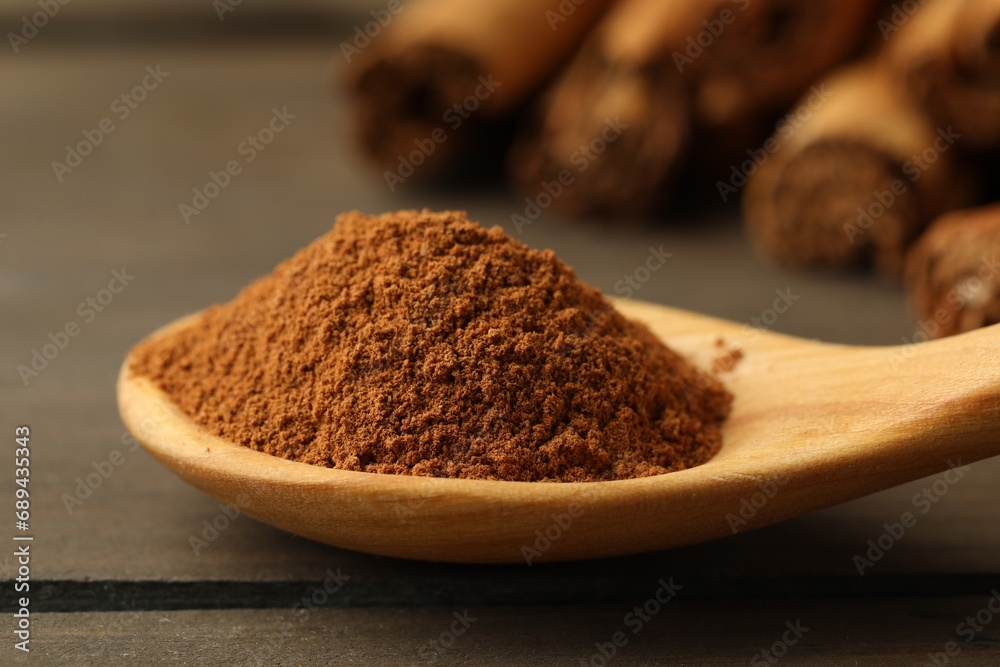 Spoon with cinnamon powder on wooden table, closeup Spoon with cinnamon powder on wooden table, closeup