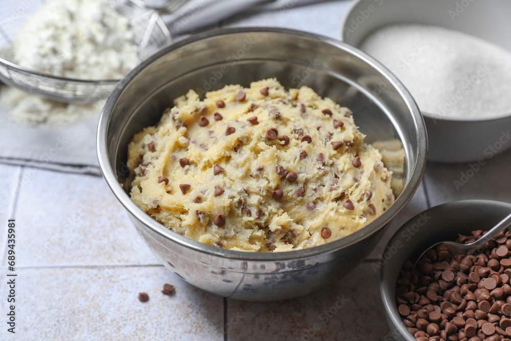 Chocolate chip cookie dough in bowl and ingredients on table, closeup Chocolate chip cookie dough in bowl and ingredients on table, closeup
