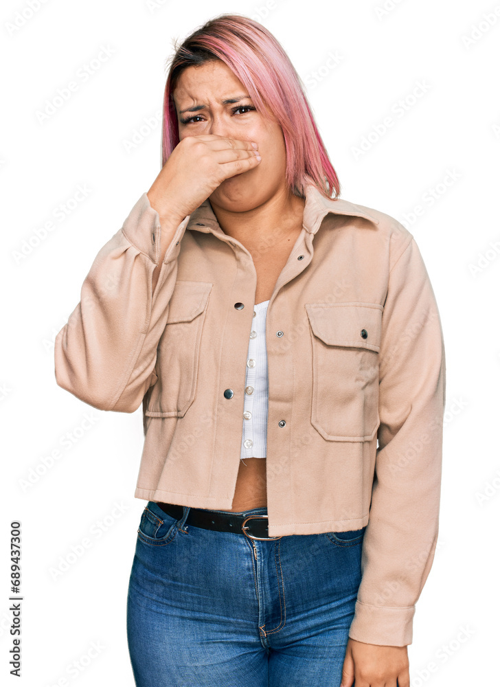 Hispanic woman with pink hair wearing casual clothes smelling something stinky and disgusting, intolerable smell, holding breath with fingers on nose. bad smell Hispanic woman with pink hair wearing casual clothes smelling something stinky and disgusting, intolerable smell, holding breath with fingers on nose. bad smell