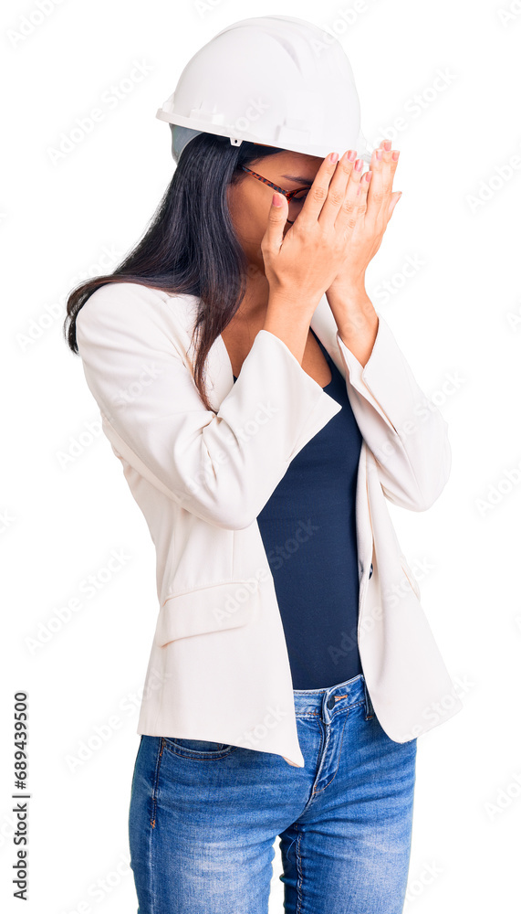 Young beautiful latin girl wearing architect hardhat and glasses with sad expression covering face with hands while crying. depression concept. Young beautiful latin girl wearing architect hardhat and glasses with sad expression covering face with hands while crying. depression concept.