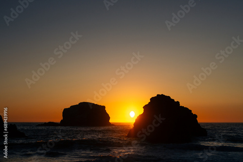 Panorama shot of Pacific ocean, small waves and rock cliffs in California beach at sunset in Usa