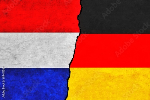 Germany and Netherlands painted flags on a wall with a crack.Netherlands and Germany relations. Germany and Netherlands flags together