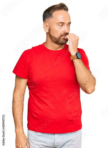 Handsome middle age man wearing casual red tshirt looking stressed and nervous with hands on mouth biting nails. anxiety problem.