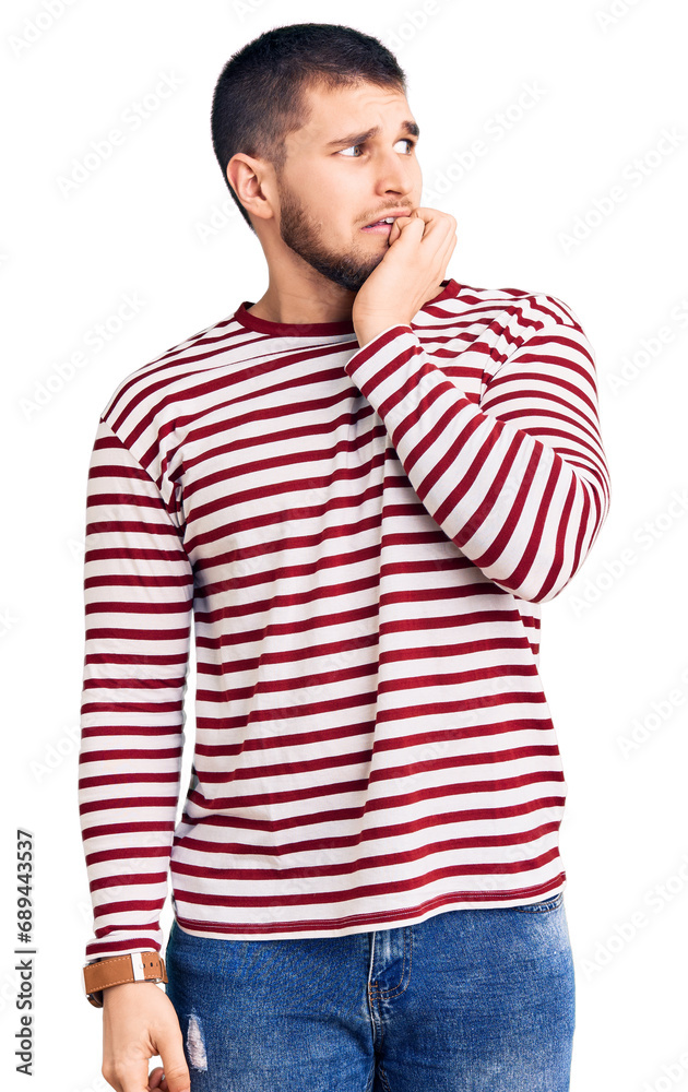 Young handsome man wearing striped sweater looking stressed and nervous with hands on mouth biting nails. anxiety problem. Young handsome man wearing striped sweater looking stressed and nervous with hands on mouth biting nails. anxiety problem.