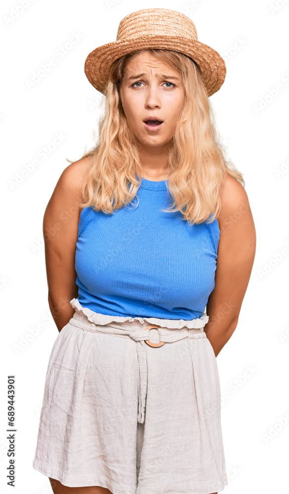 Young blonde girl wearing summer hat scared and amazed with open mouth for surprise, disbelief face Young blonde girl wearing summer hat scared and amazed with open mouth for surprise, disbelief face
