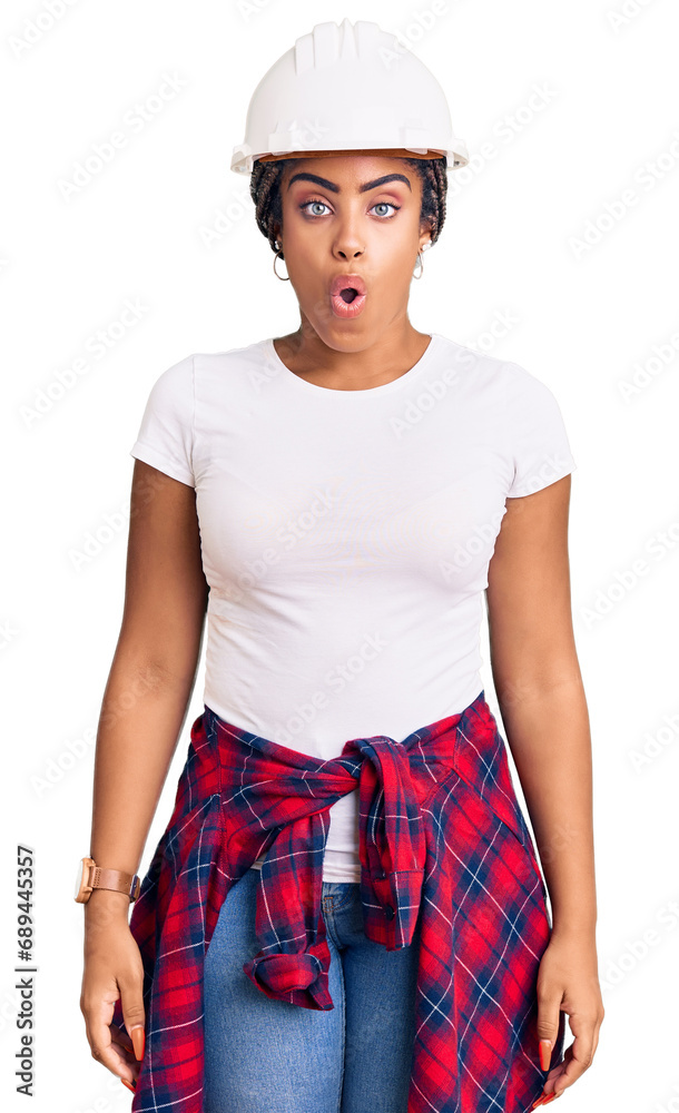 Young african american woman with braids wearing hardhat and builder clothes scared and amazed with open mouth for surprise, disbelief face Young african american woman with braids wearing hardhat and builder clothes scared and amazed with open mouth for surprise, disbelief face