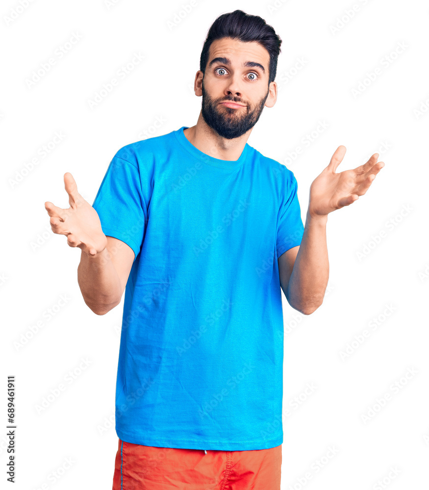 Young handsome man with beard wearing casual t-shirt clueless and confused expression with arms and hands raised. doubt concept. Young handsome man with beard wearing casual t-shirt clueless and confused expression with arms and hands raised. doubt concept.