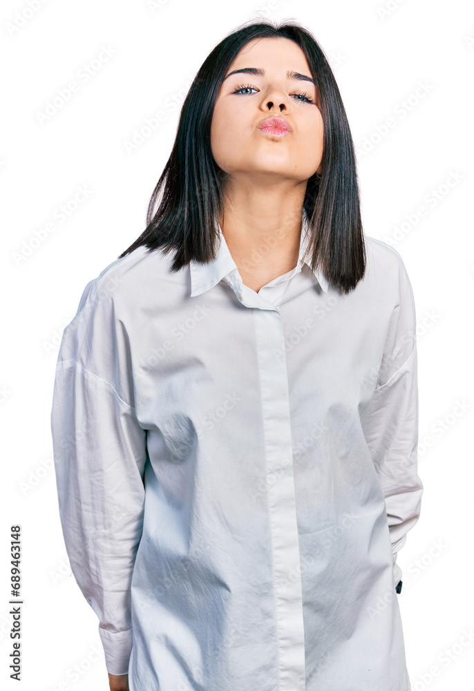 Young brunette woman with blue eyes wearing oversize white shirt looking at the camera blowing a kiss on air being lovely and sexy. love expression. Young brunette woman with blue eyes wearing oversize white shirt looking at the camera blowing a kiss on air being lovely and sexy. love expression.