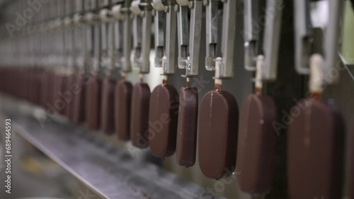 Industrial ice cream factory. Automation and technology in the food production business. View of a machine transporting cream popsicles coated in chocolate.