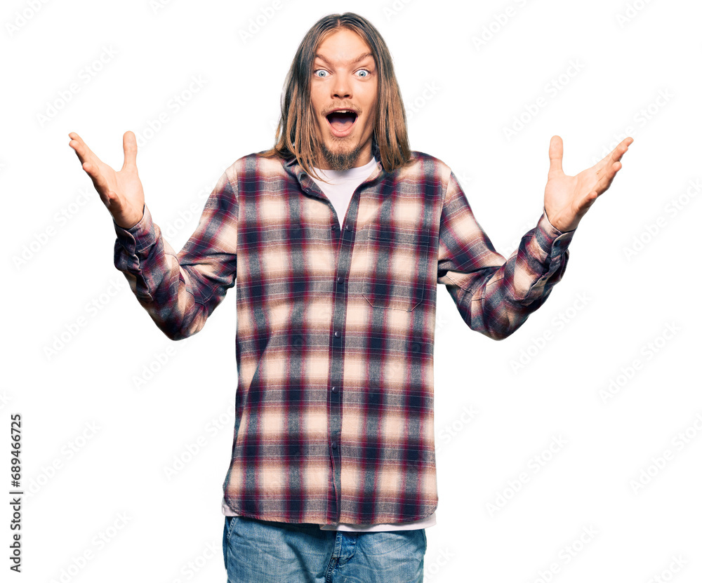 Handsome caucasian man with long hair wearing hipster shirt celebrating crazy and amazed for success with arms raised and open eyes screaming excited. winner concept