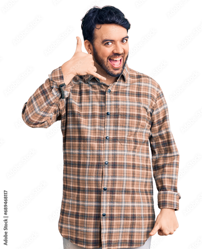 Young hispanic man wearing casual clothes smiling doing phone gesture with hand and fingers like talking on the telephone. communicating concepts. Young hispanic man wearing casual clothes smiling doing phone gesture with hand and fingers like talking on the telephone. communicating concepts.