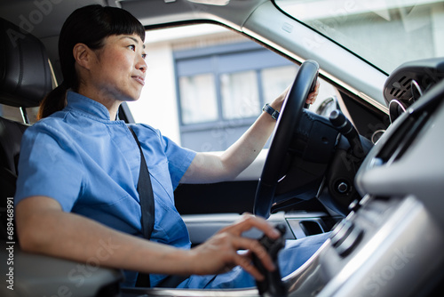 Young asian woman in nurse uniform driving car