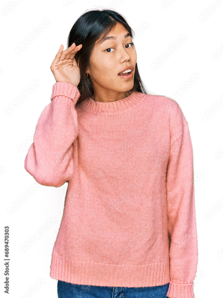 Beautiful young asian woman wearing casual winter sweater smiling with hand over ear listening an hearing to rumor or gossip. deafness concept.