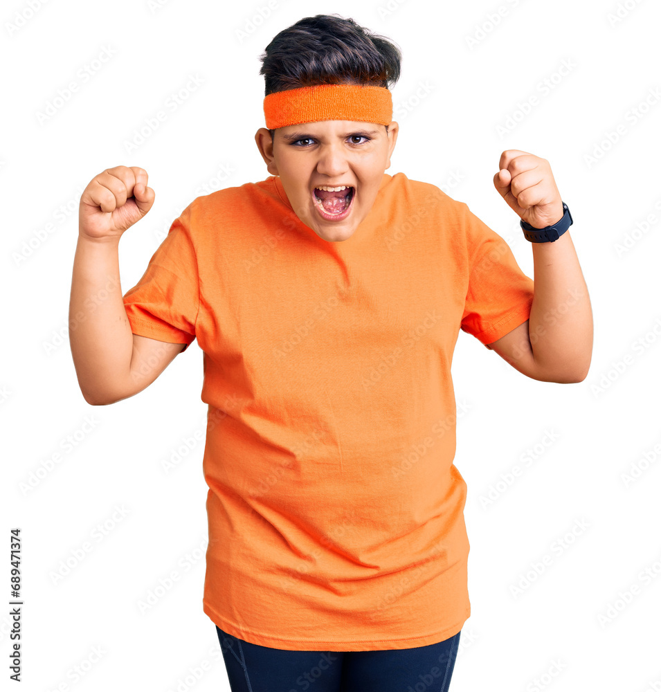Little boy kid wearing sportswear angry and mad raising fists frustrated and furious while shouting with anger. rage and aggressive concept. Little boy kid wearing sportswear angry and mad raising fists frustrated and furious while shouting with anger. rage and aggressive concept.