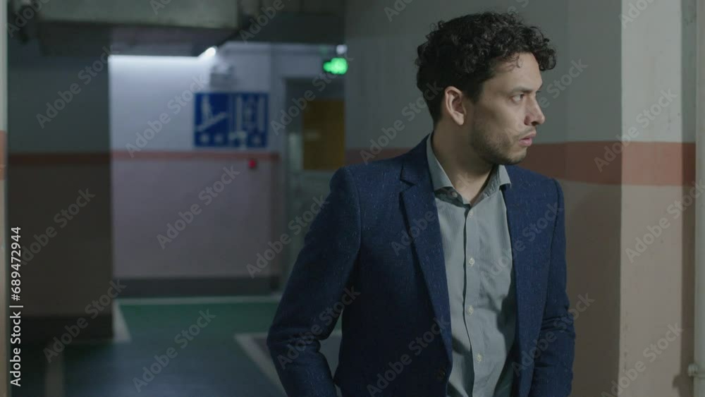 Man in suit walks into underground parking and gets a feeling of danger ahead, looks around. Slow motion. Man in suit walks into underground parking and gets a feeling of danger ahead, looks around. Slow motion.