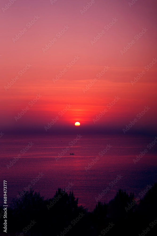 The beautiful sun setting on the horizon with a view of the sea in the foreground.
