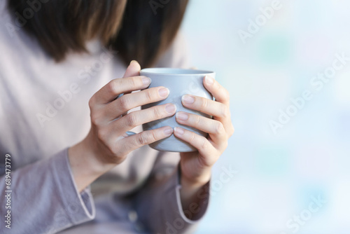 Woman's hand holding a gray cup for hot drinks.