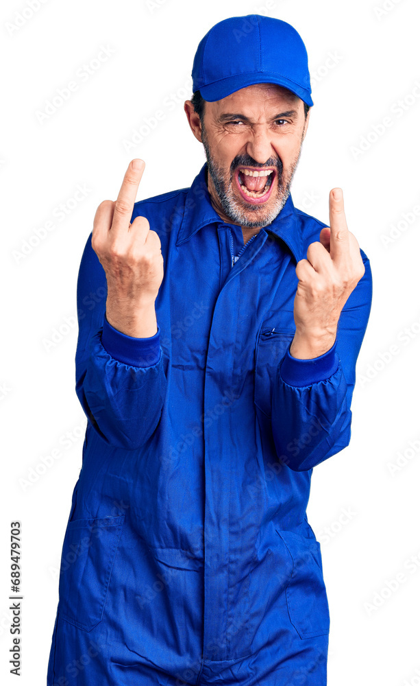 Middle age handsome man wearing mechanic uniform showing middle finger doing fuck you bad expression, provocation and rude attitude. screaming excited