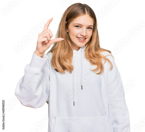 Beautiful young caucasian girl wearing casual sweatshirt smiling and confident gesturing with hand doing small size sign with fingers looking and the camera. measure concept.