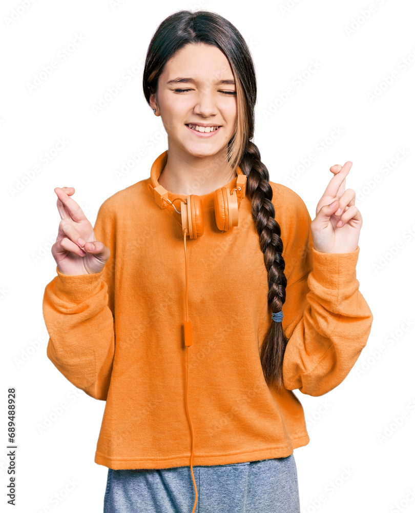 Φωτογραφία Young brunette girl with long hair wearing sweatshirt and headphones gesturing finger crossed smiling with hope and eyes closed