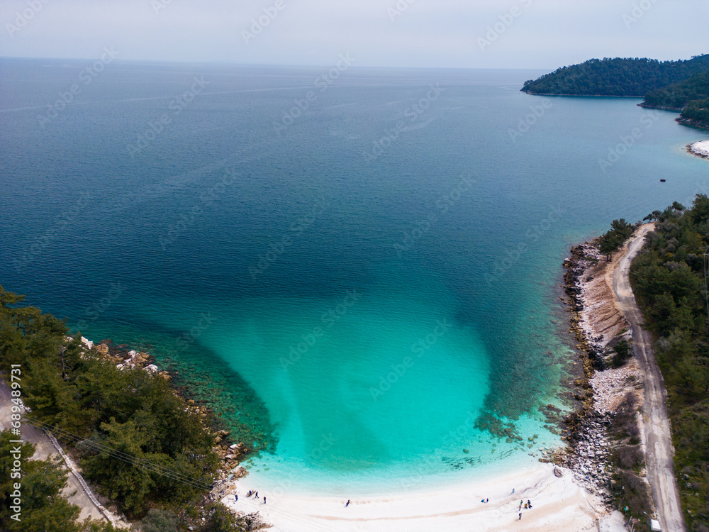 The beach with white marble pebbles and turquoise sea on the Greek island of Thassos. Aerial view. The contrast of the pristine white pebbles against the vivid blue sea creates a mesmerizing view.