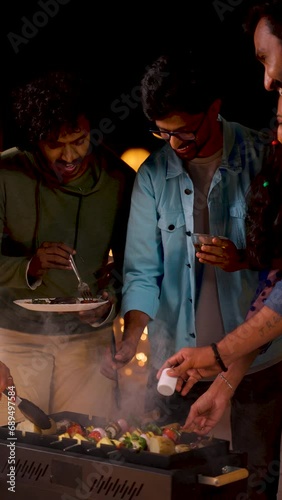 vertical shot, Group of friends busy cooking barbecue grills for dinner during night party - concept of togetherness, birthday gathering and celebration