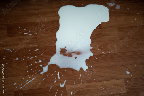 Spilled milk on the floor. White spot of liquid with splashes. Healthy beverage dropped by accident