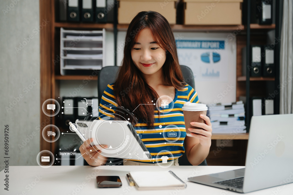 Asian Woman hand using a laptop, smartphone and tablet and writing notebook at the office of her business online shopping. In home with virtual icon Asian Woman hand using a laptop, smartphone and tablet and writing notebook at the office of her business online shopping. In home with virtual icon