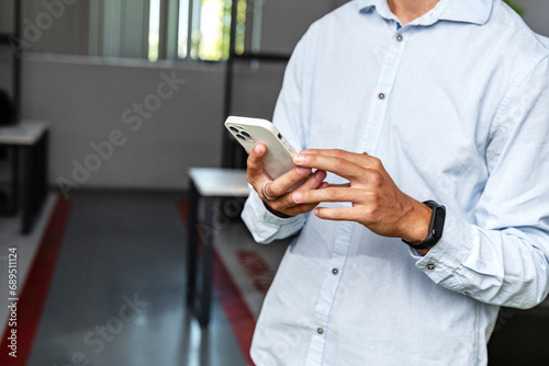 Close up photo of an entrepreneur using his mobile phone in the office