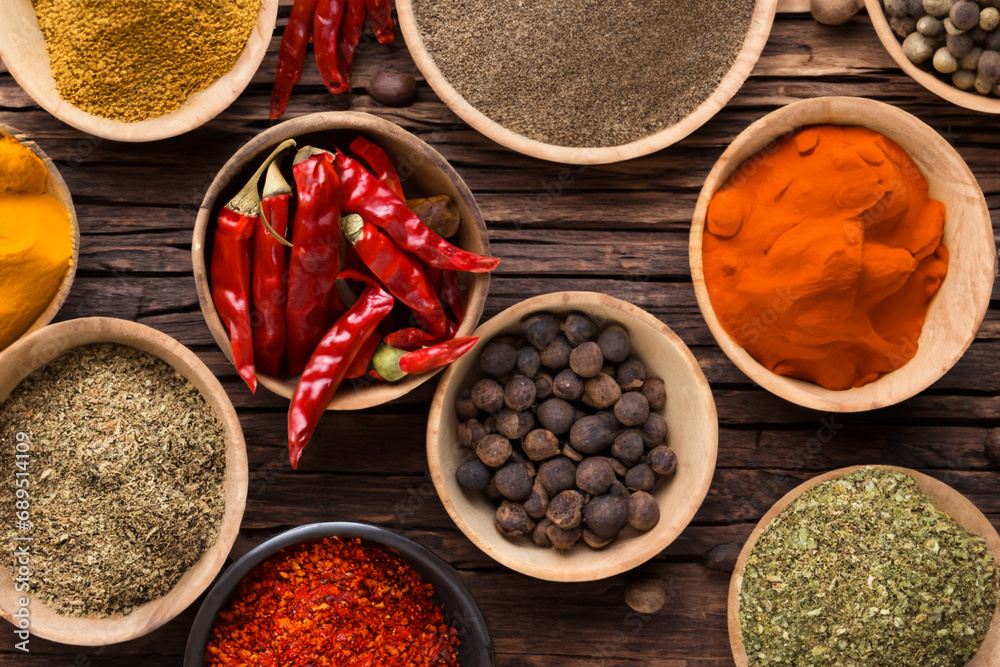 Variety of spices in wooden bowls on old wooden table background. Variety of spices in wooden bowls on old wooden table background.