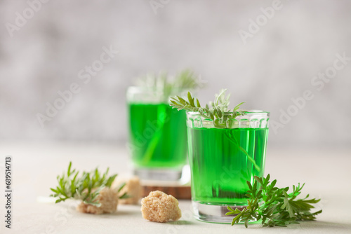 Absinthe drink in glass on light background with the absinthe plant and sugar photo