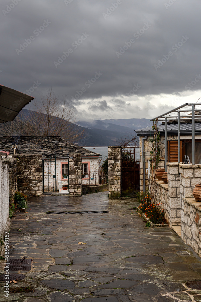 Narrow street with houses in a village (Greece, Epirus) near a lake