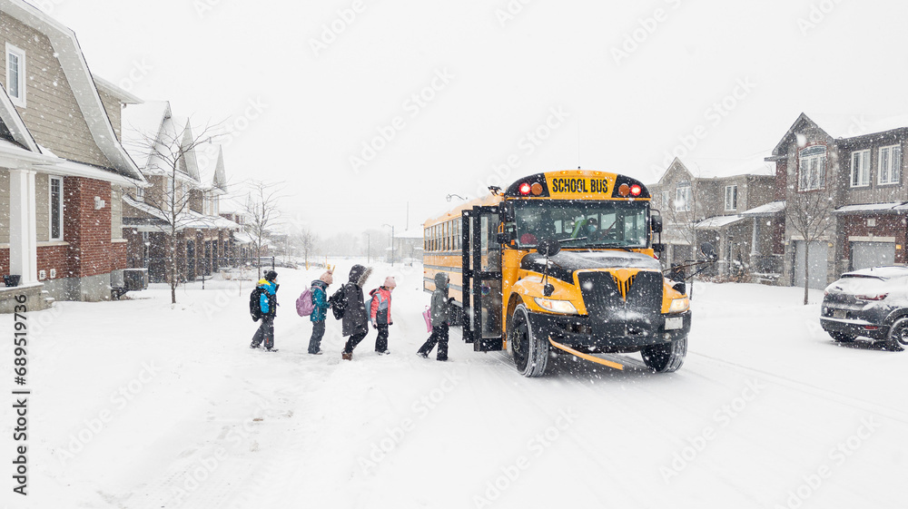 unrecognizable children waiting for bus in snowy neighbourhood during winter - obrazy, fototapety, plakaty 