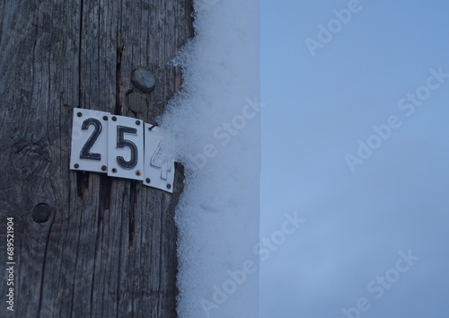Nummerierter alter Stromleistungsmast mit Schneeverwehung