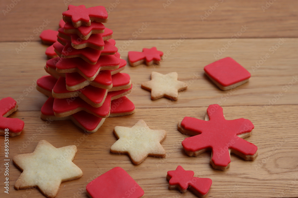 Christmas tree made of star shaped shortcrust cookies with red sugar glaze and other cookies on wooden table. Christmas background Christmas tree made of star shaped shortcrust cookies with red sugar glaze and other cookies on wooden table. Christmas background