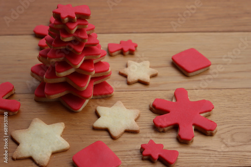 Christmas tree made of star shaped shortcrust cookies with red sugar glaze and other cookies on wooden table. Christmas background